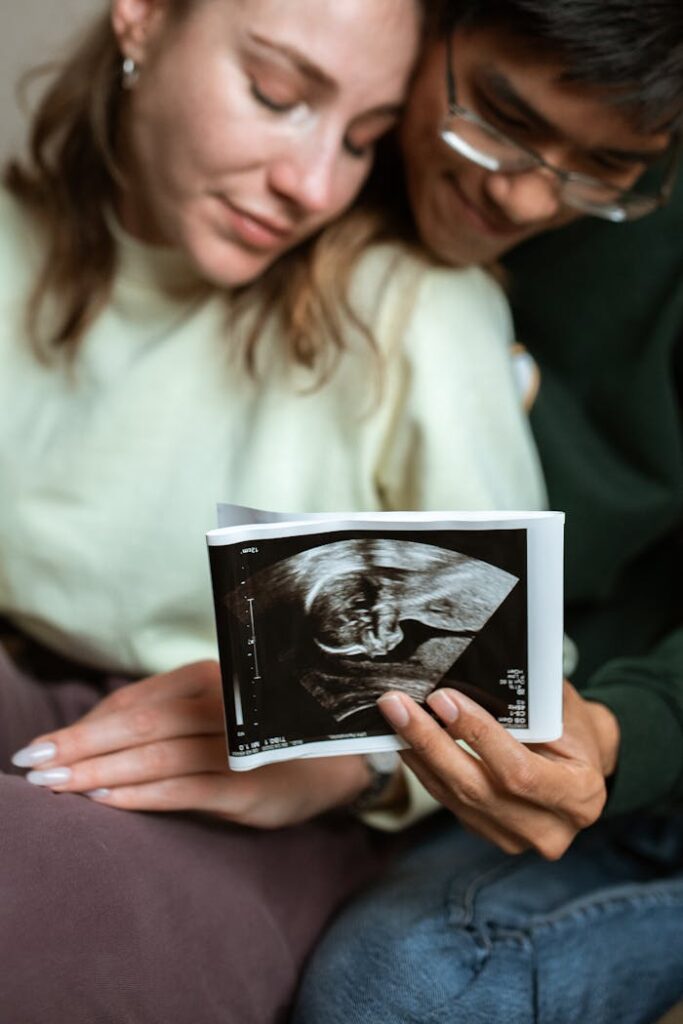 A couple lovingly holds an ultrasound photo, celebrating pregnancy indoors.